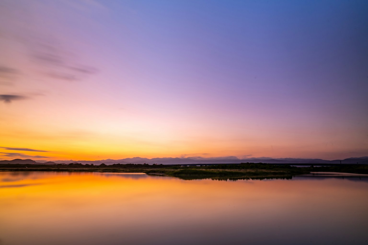 Pemandangan sunset yang indah dengan air tenang yang memantulkan langit