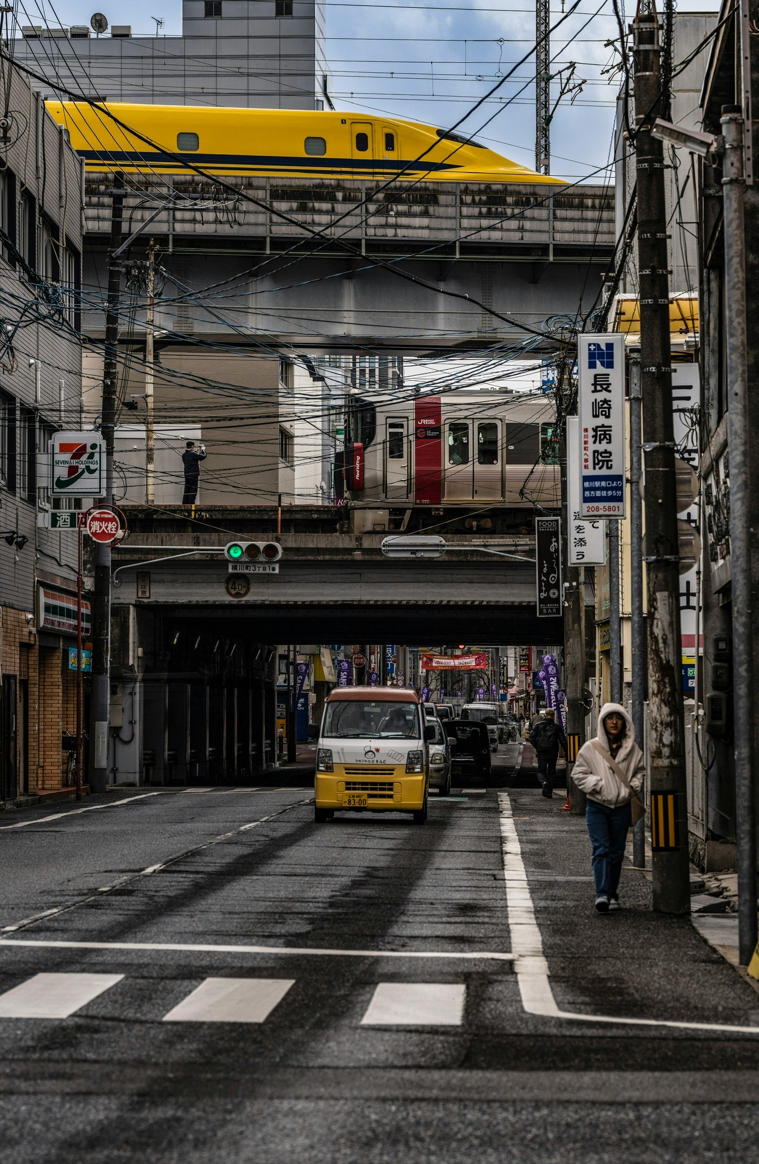 Le Shinkansen « Doctor Yellow » circulant dans une rue étroite avec une voiture jaune