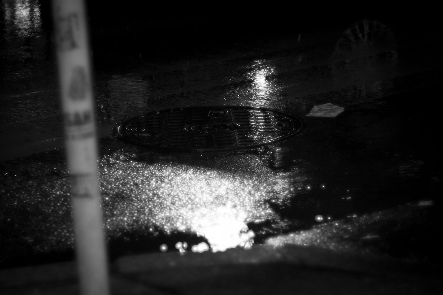 Lichtreflexion in einer Pfütze auf einer dunklen Straße