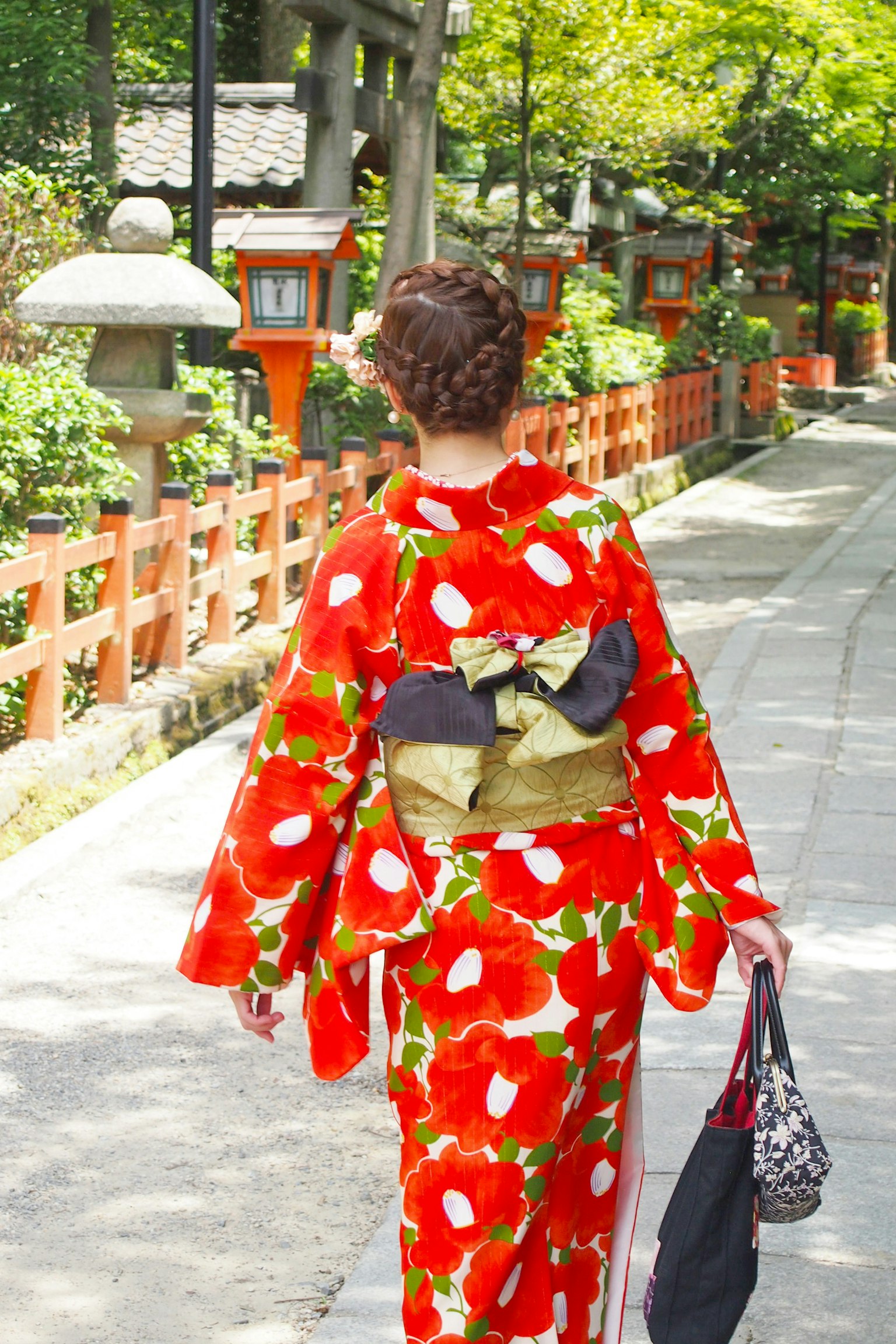 Frau in einem roten Blumenkimono, die einen Weg entlanggeht