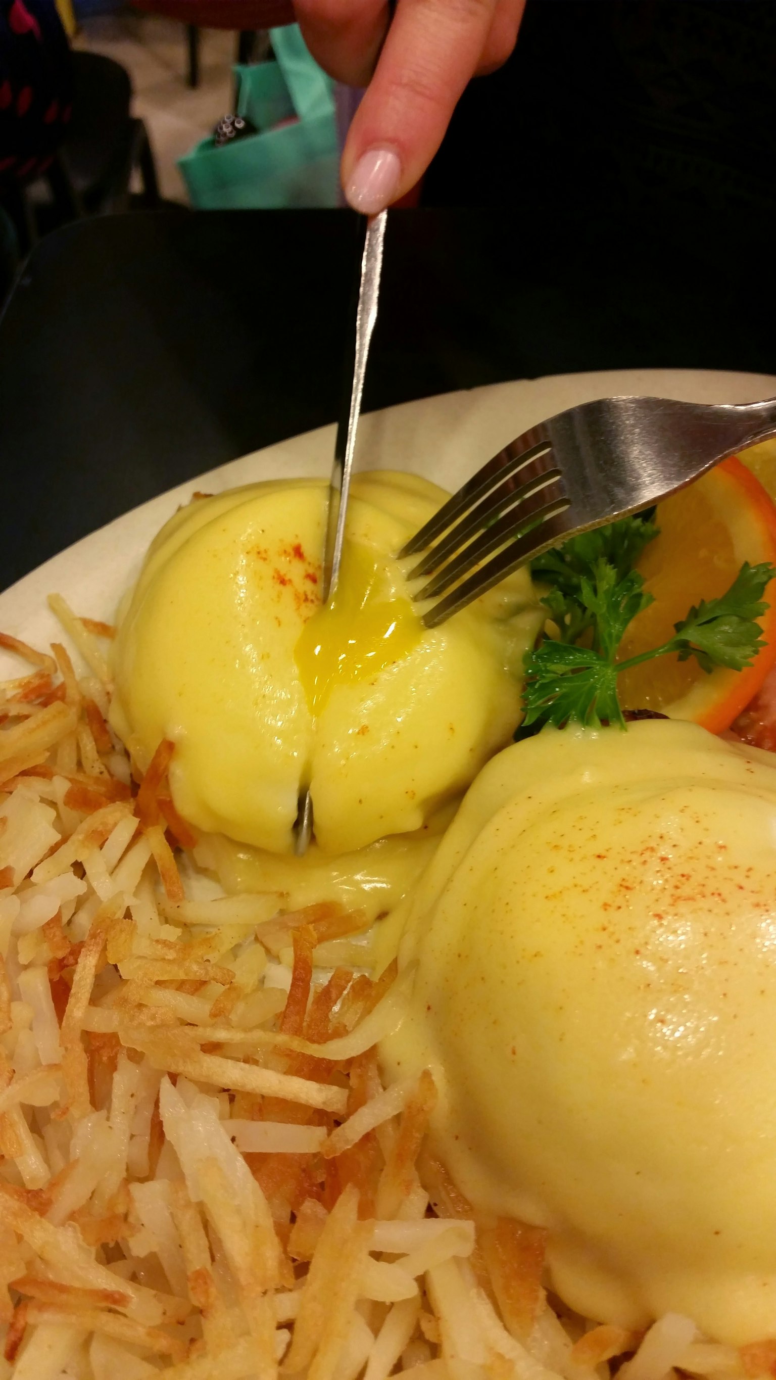 Due uova poached tagliate che rivelano il tuorlo su un piatto con hash browns