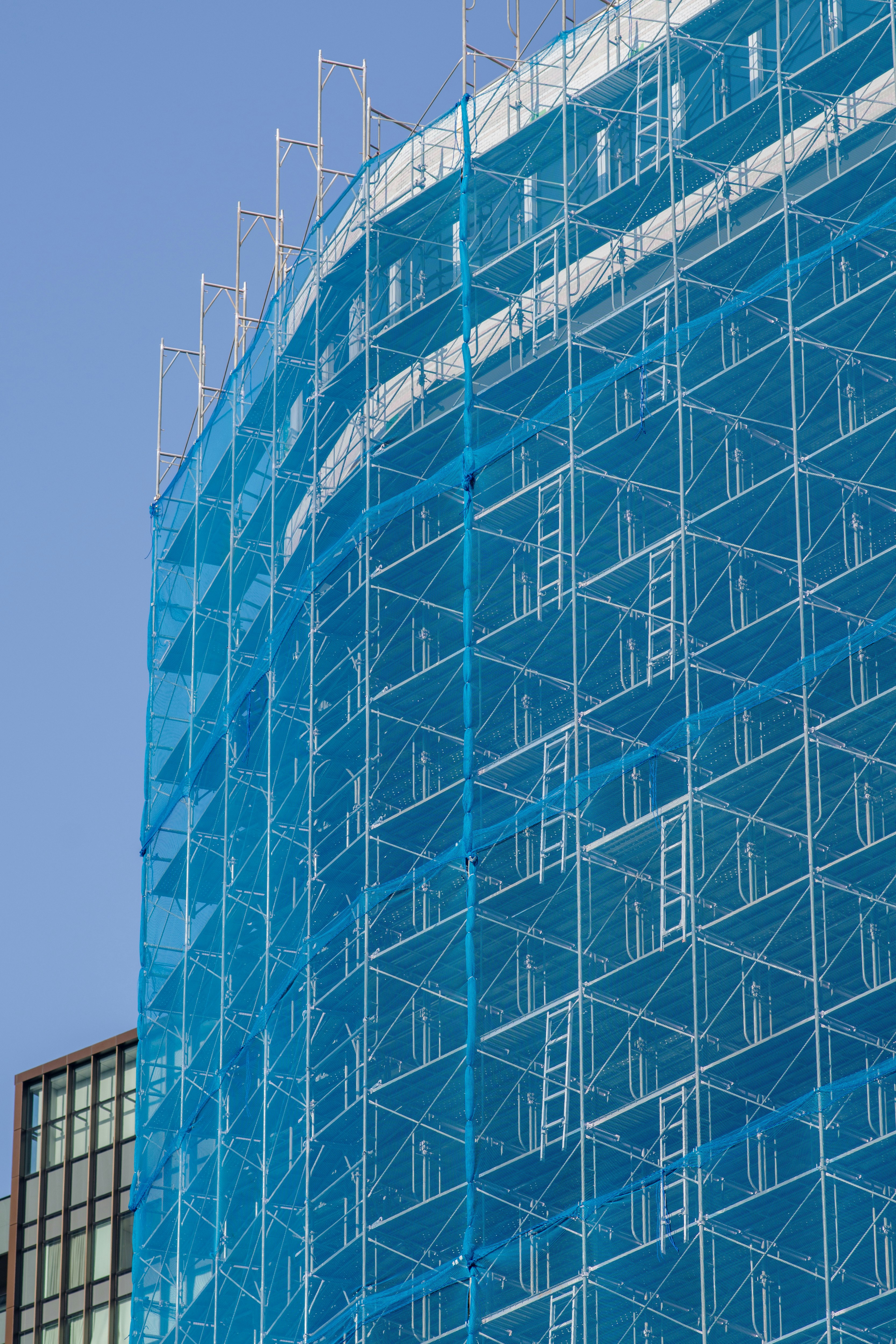 scaffolding on a high-rise building covered with blue netting