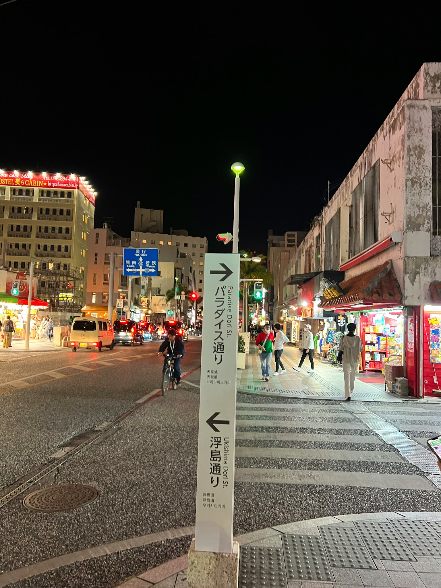 Straßenschild bei Nacht mit Geschäften im Hintergrund
