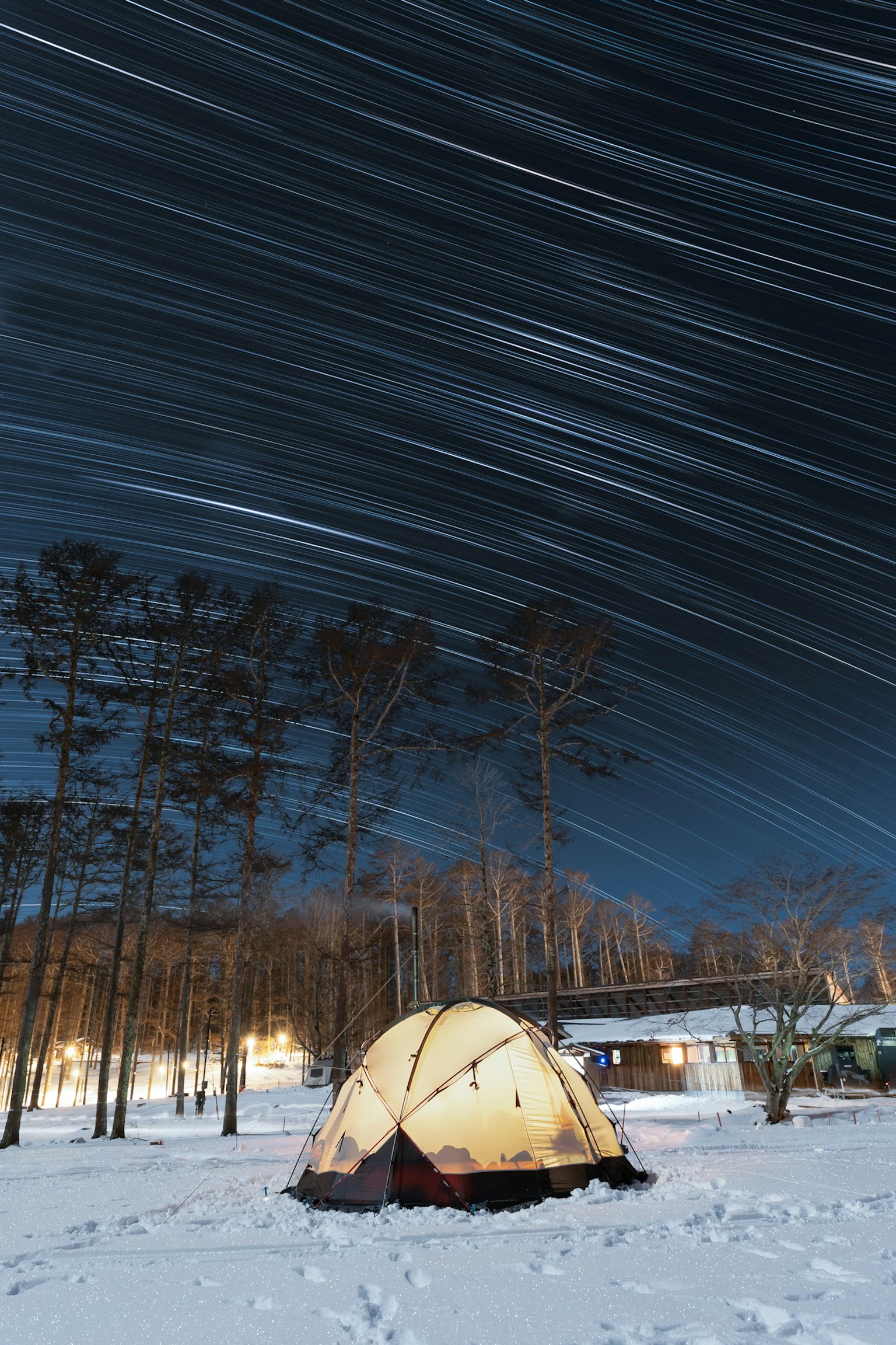 雪覆盖的森林中的帐篷和夜空中的星轨