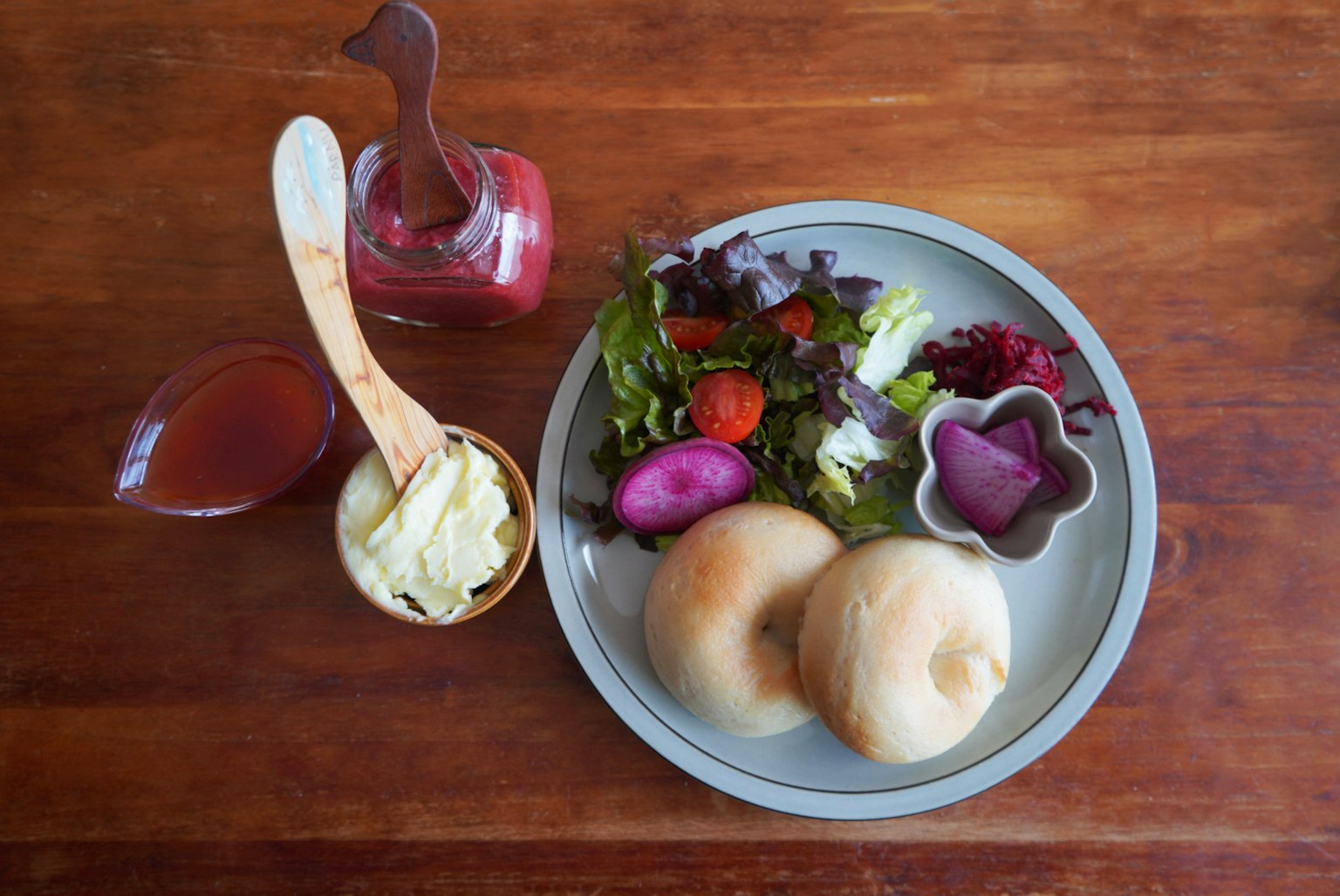 Un plato con ensalada y panes junto a una botella de salsa