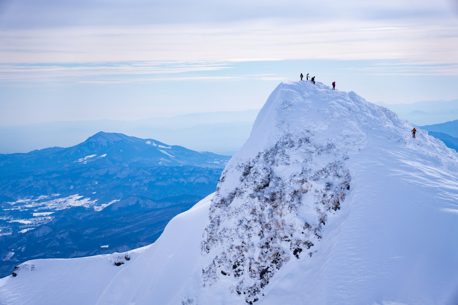 눈 덮인 산 정상에 서 있는 등반가들과 멋진 풍경
