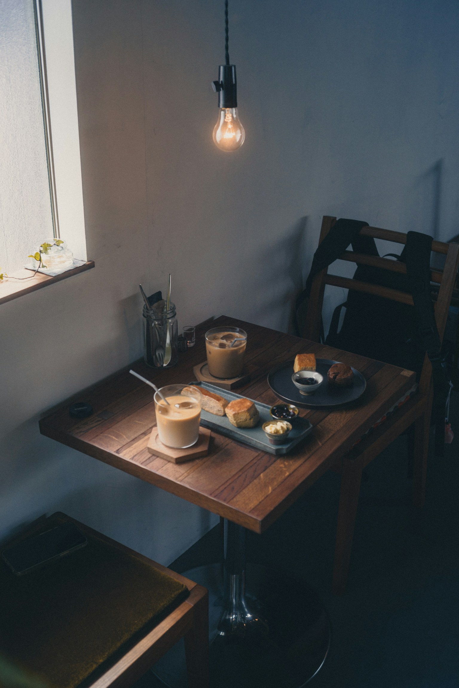 木製のテーブルにコーヒーとデザートが並ぶカフェの静かな風景