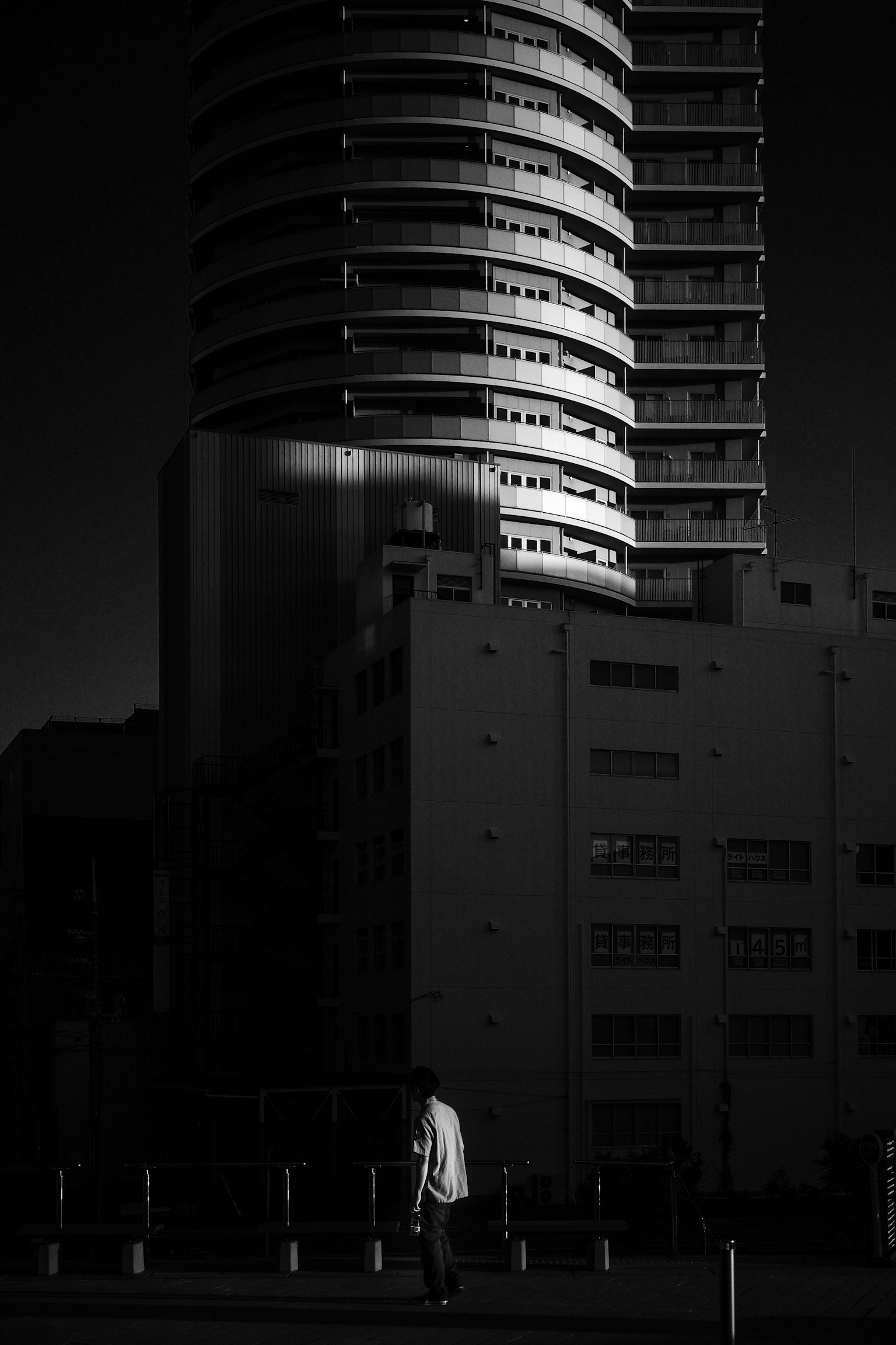 Paisaje urbano en blanco y negro con un rascacielos y una persona caminando
