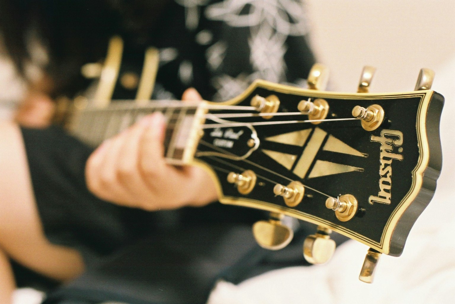 Primer plano de la cabeza de una guitarra Gibson con una persona sosteniéndola