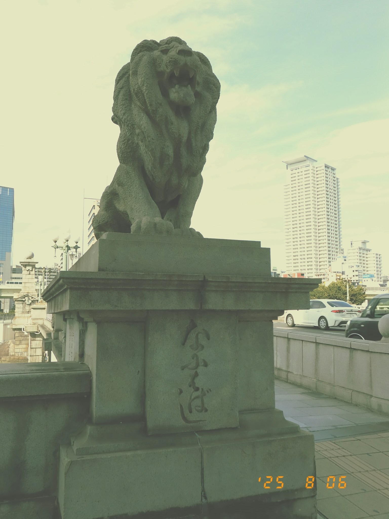 Pedestal de piedra con una escultura de león y edificios modernos al fondo