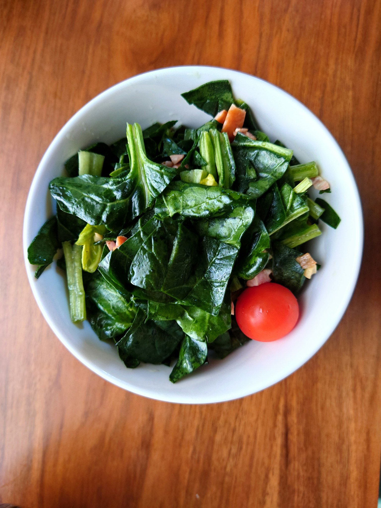 碗中的新鲜菠菜沙拉和一个番茄