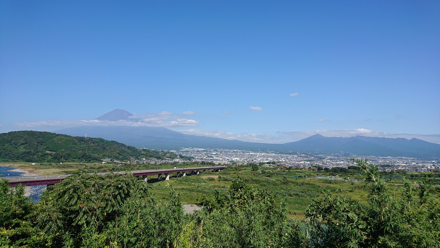 Vista panoramica di montagne e fiume sotto il cielo blu campi verdi e città lontana visibili