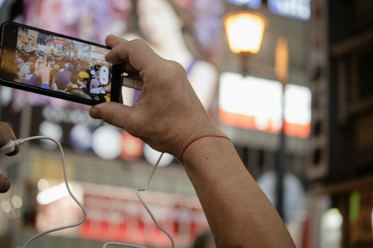 Eine Hand hält ein Smartphone und fängt eine lebendige Straßenszene ein