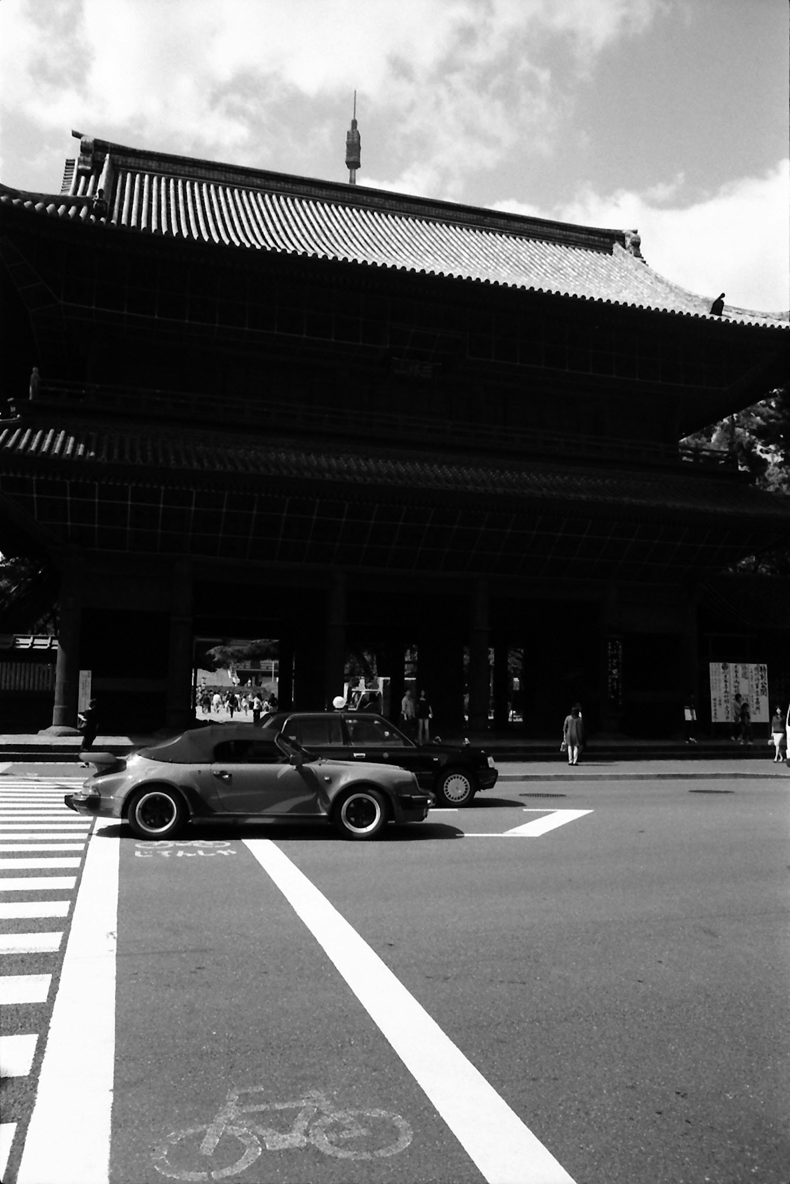 Black and white photo of a traditional building with a car crossing the intersection