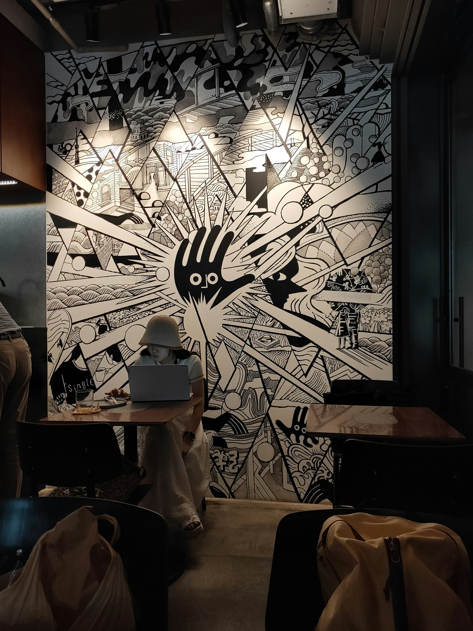 Interior kafe dengan mural mencolok yang menampilkan desain tangan hitam