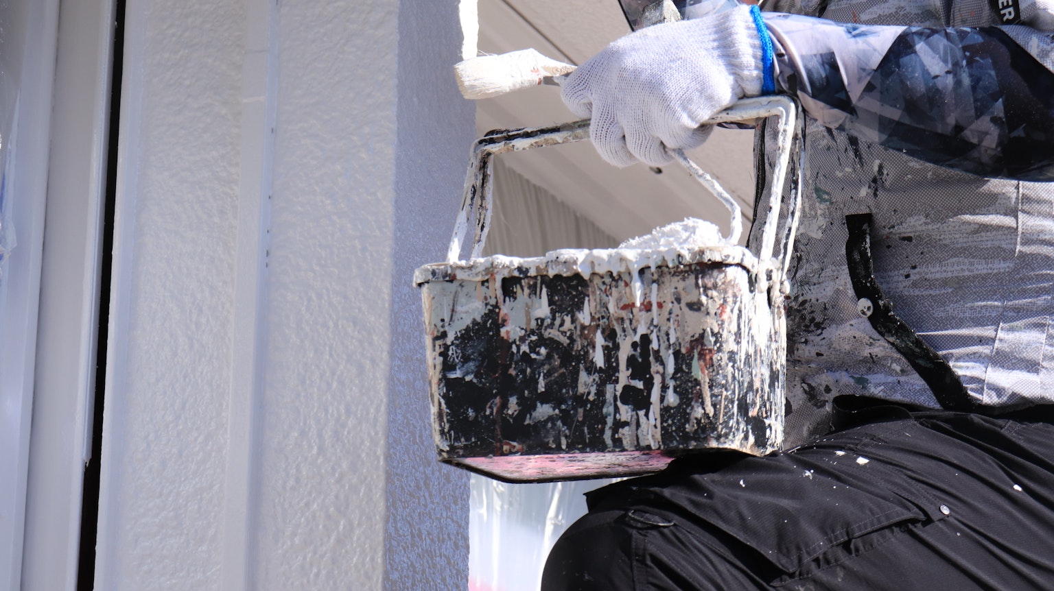 Une personne tenant un seau de peinture en train de peindre