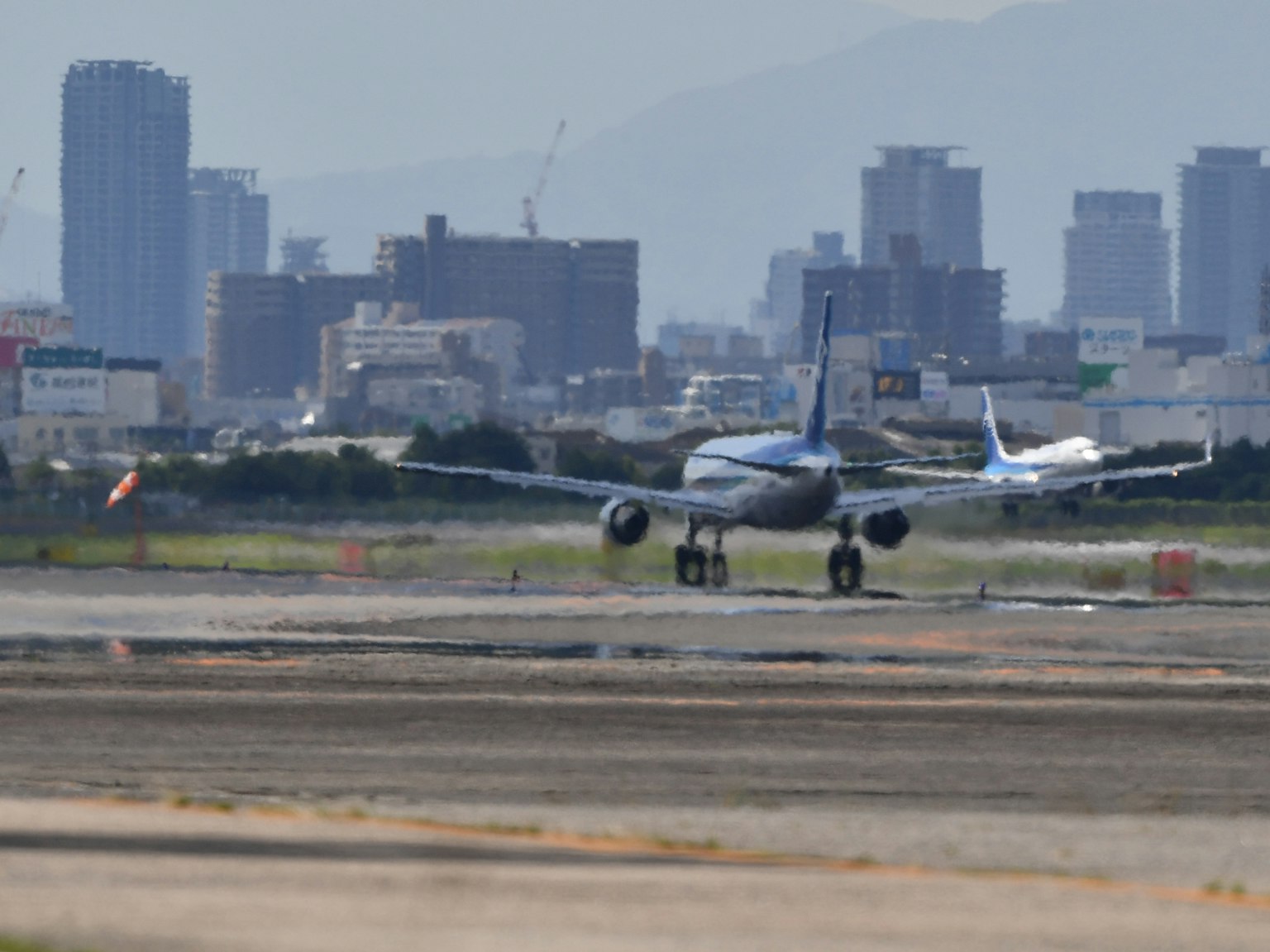 공항 활주로에서 이륙하는 비행기와 배경에 도시 스카이라인