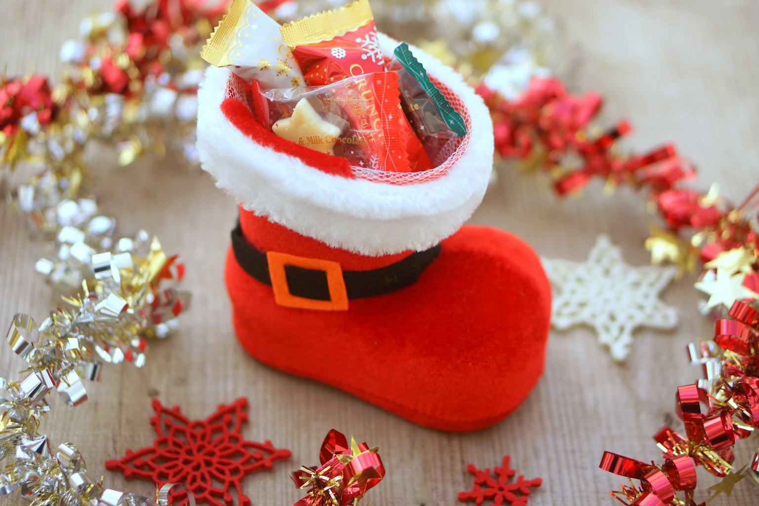 Sepatu Santa merah yang diisi permen dikelilingi oleh dekorasi meriah