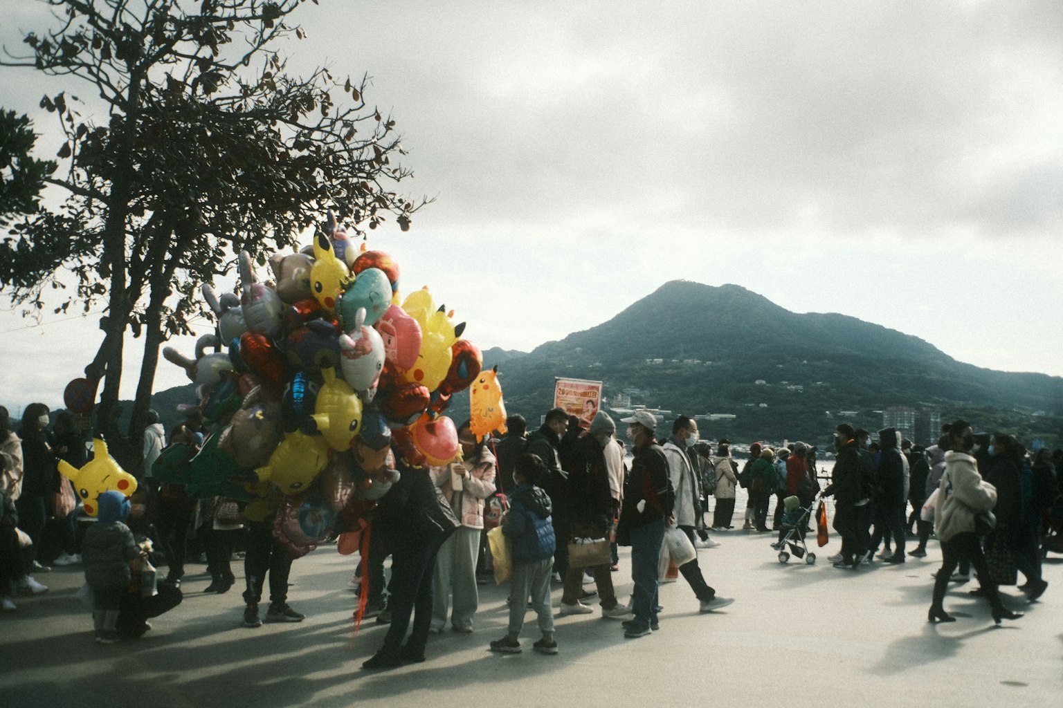 Crowd of people with colorful balloons near a mountain