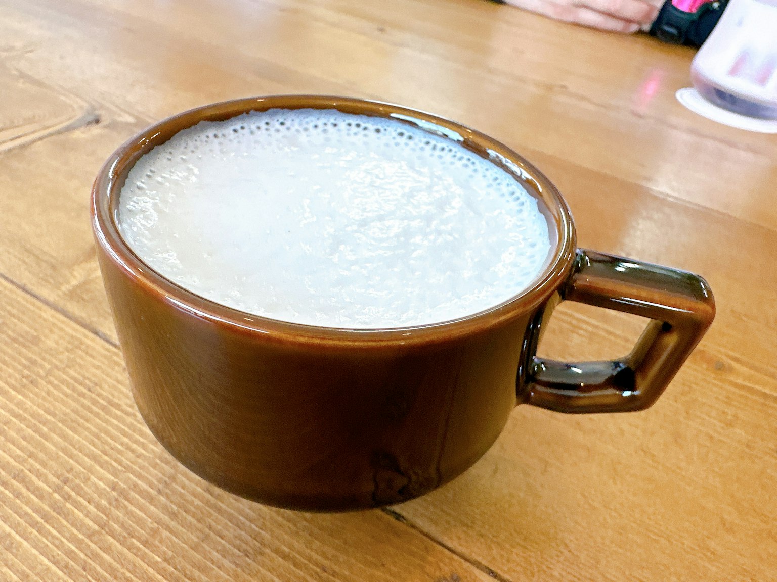 Minuman berbusa dalam cangkir cokelat