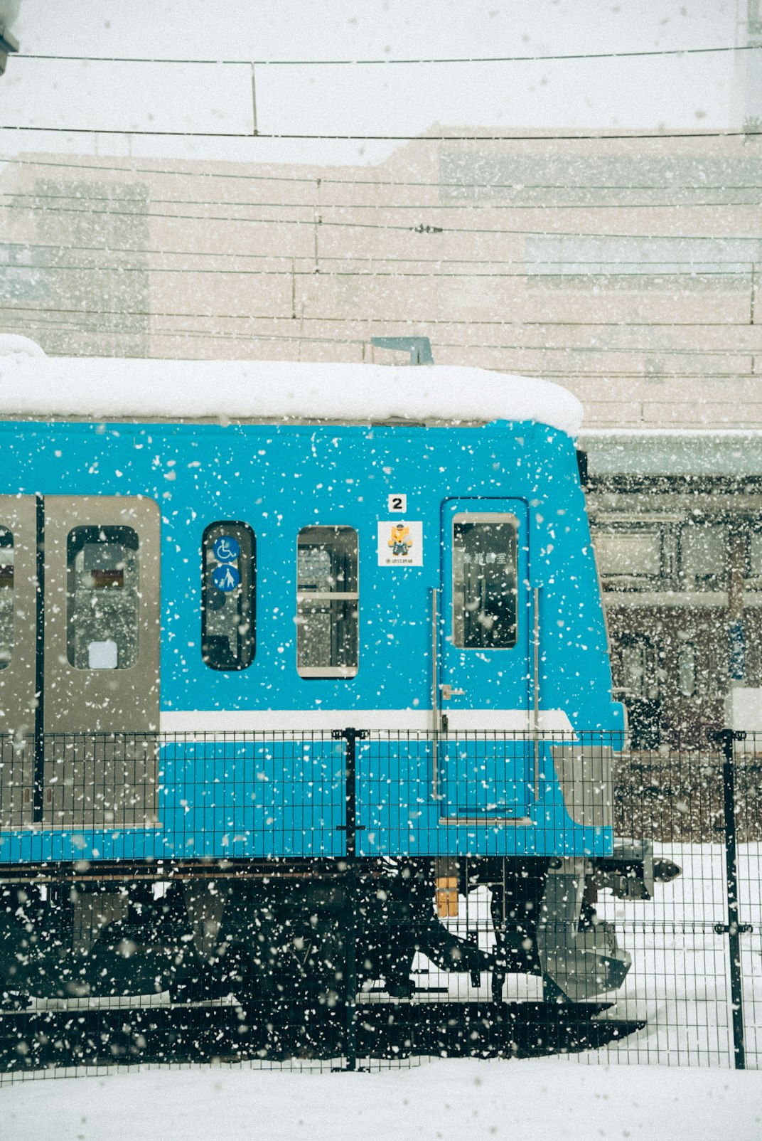 Zug der Ōmi-Eisenbahn steht im Schneefall am Bahnsteig