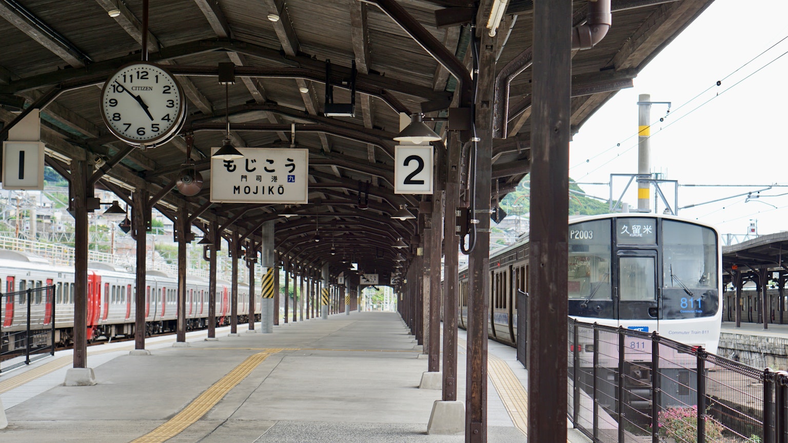 Plataforma de estación de tren con reloj y tren
