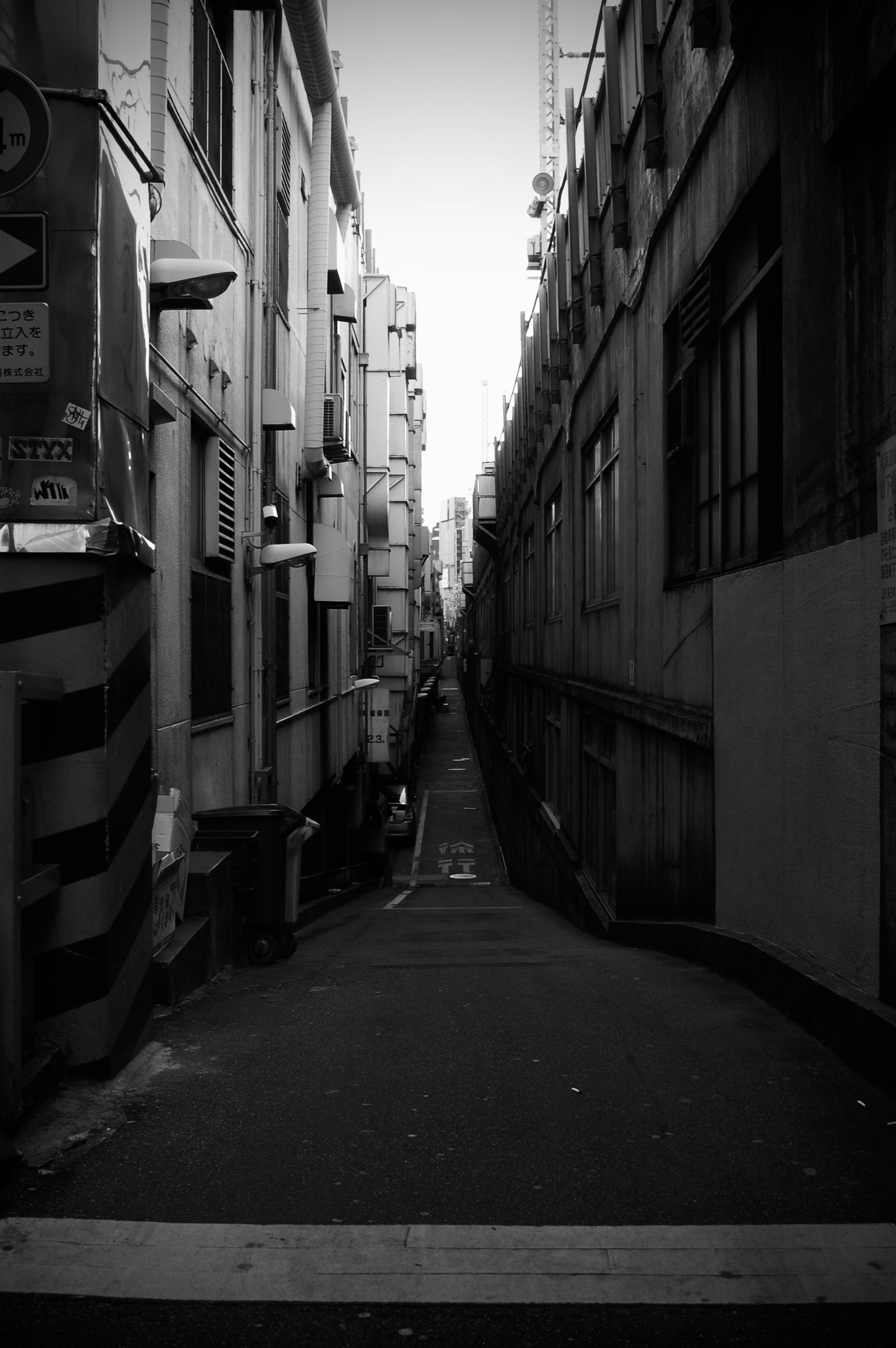 狭い路地が続くモノクロの都市風景 建物が両側に立ち並ぶ