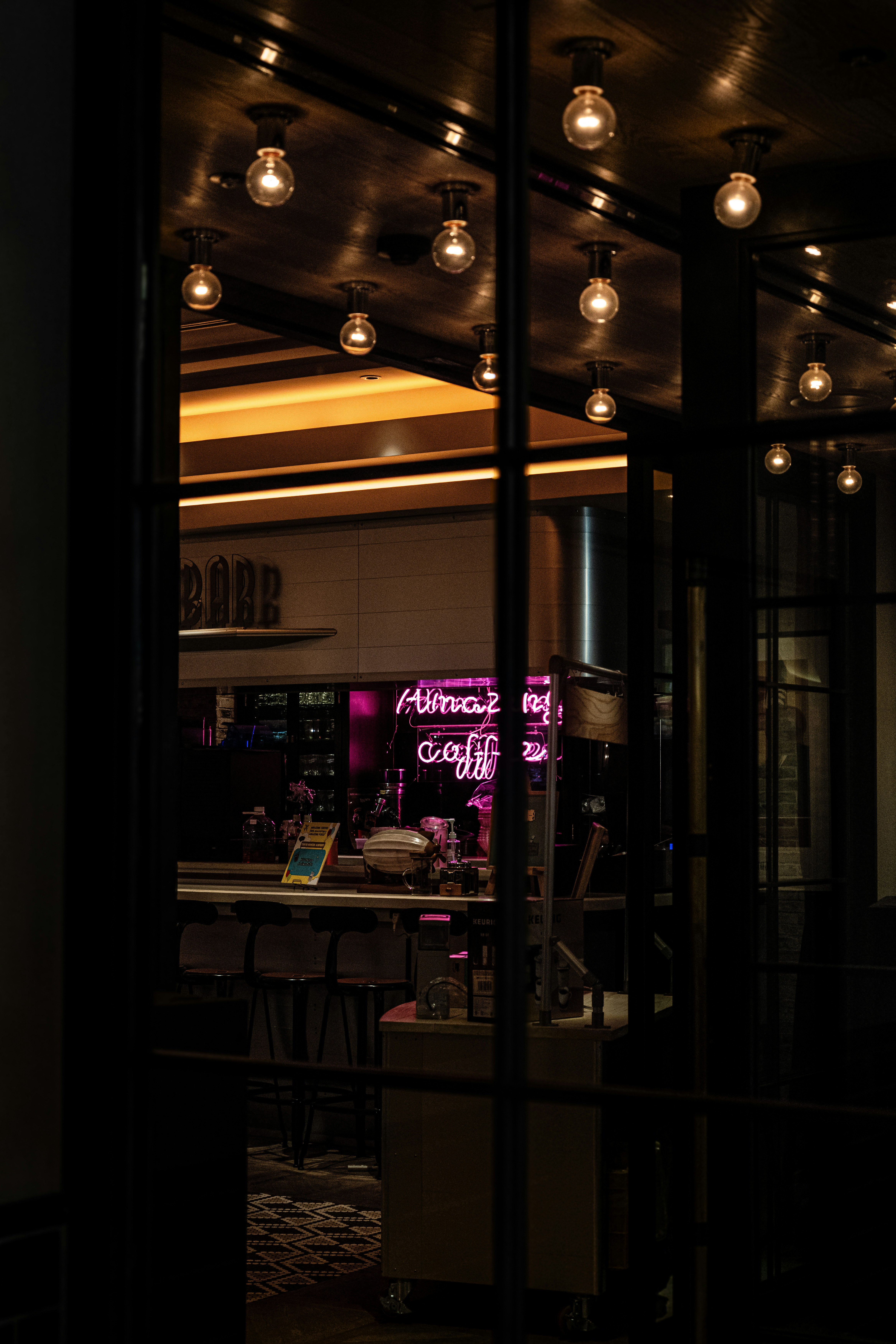 ガラス越しに見える店内のネオン看板とテーブル