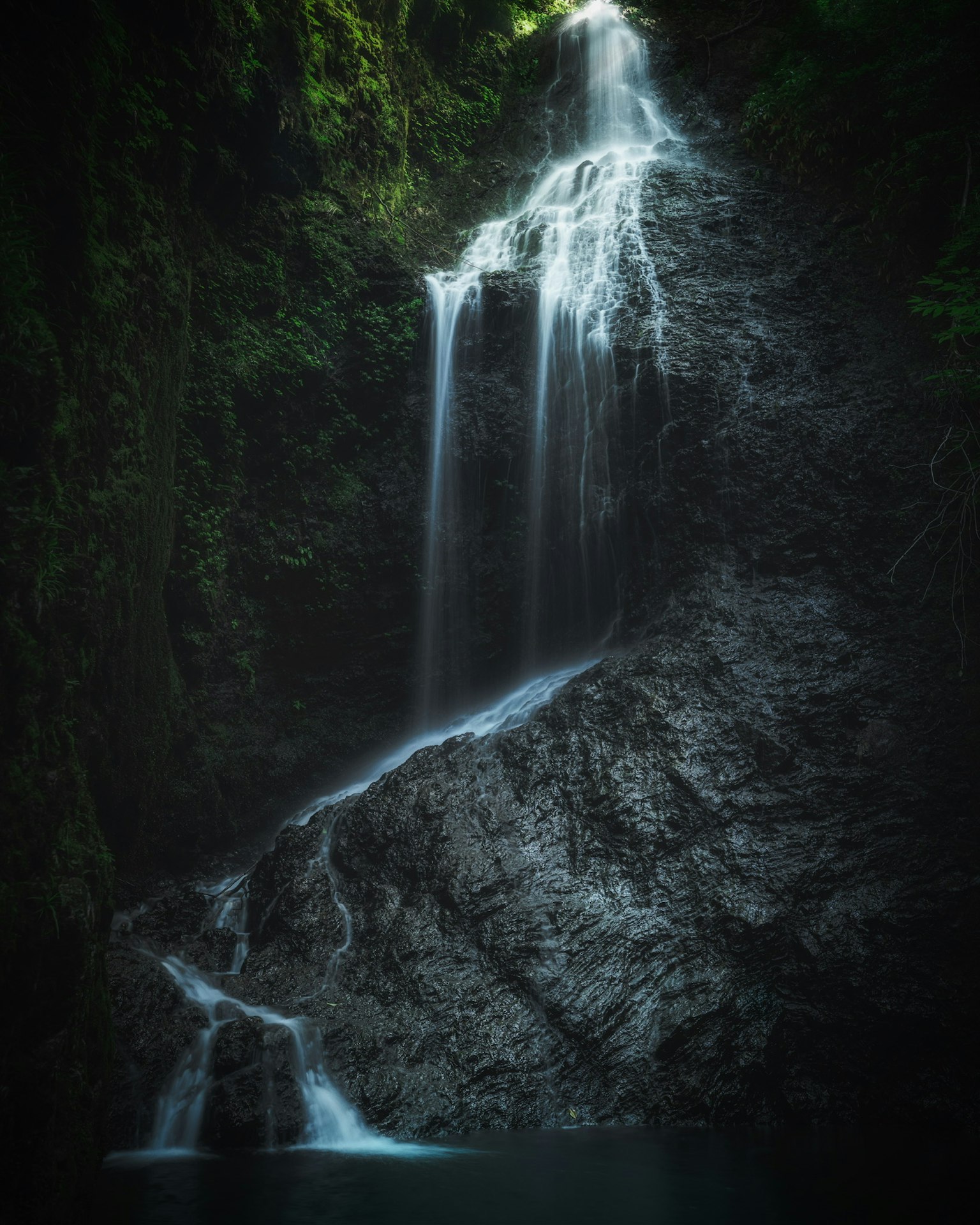 A stunning waterfall cascading down rocky cliffs surrounded by lush greenery