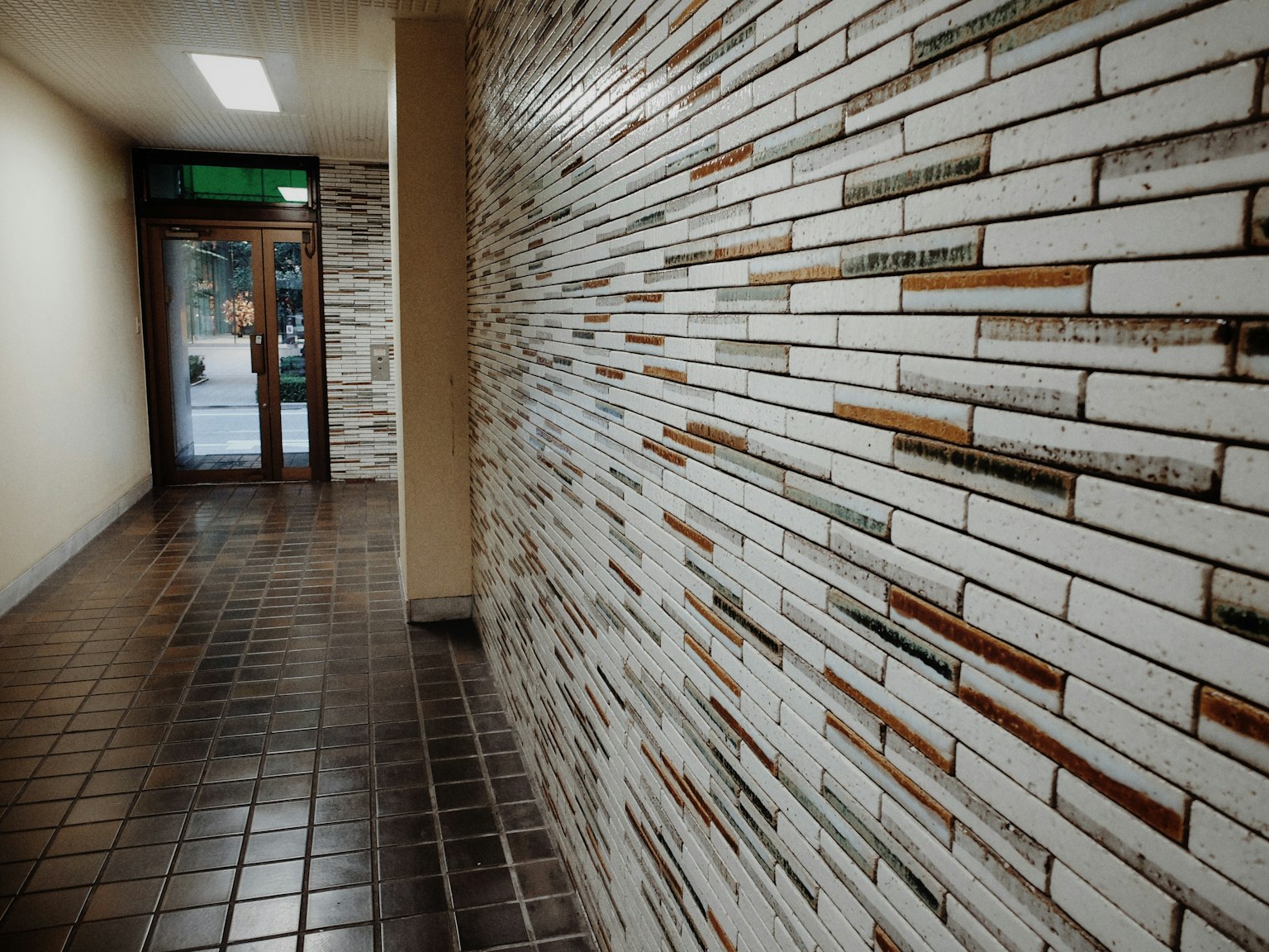 Photo d'un couloir avec un mur carrelé blanc et un sol carrelé noir