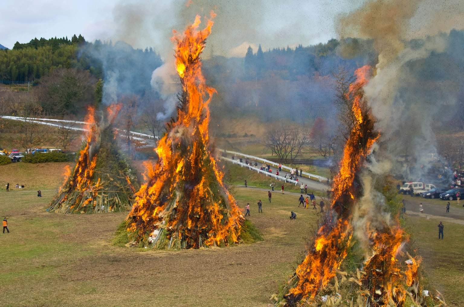 Große Feuer brennen mit aufsteigendem Rauch auf einer grasbewachsenen Fläche