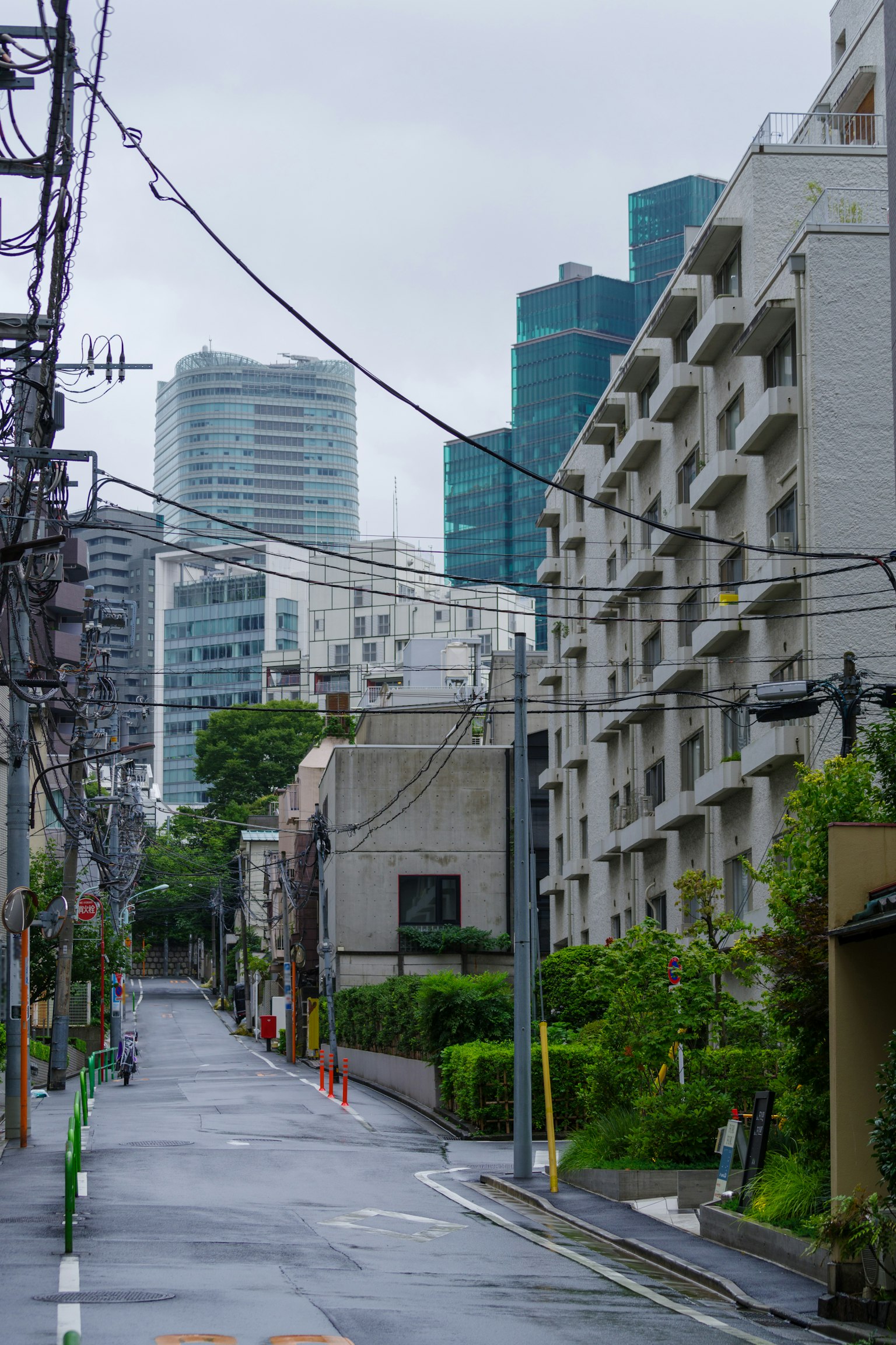 Scène urbaine par un jour de pluie avec des bâtiments modernes et des zones résidentielles le long d'une rue calme