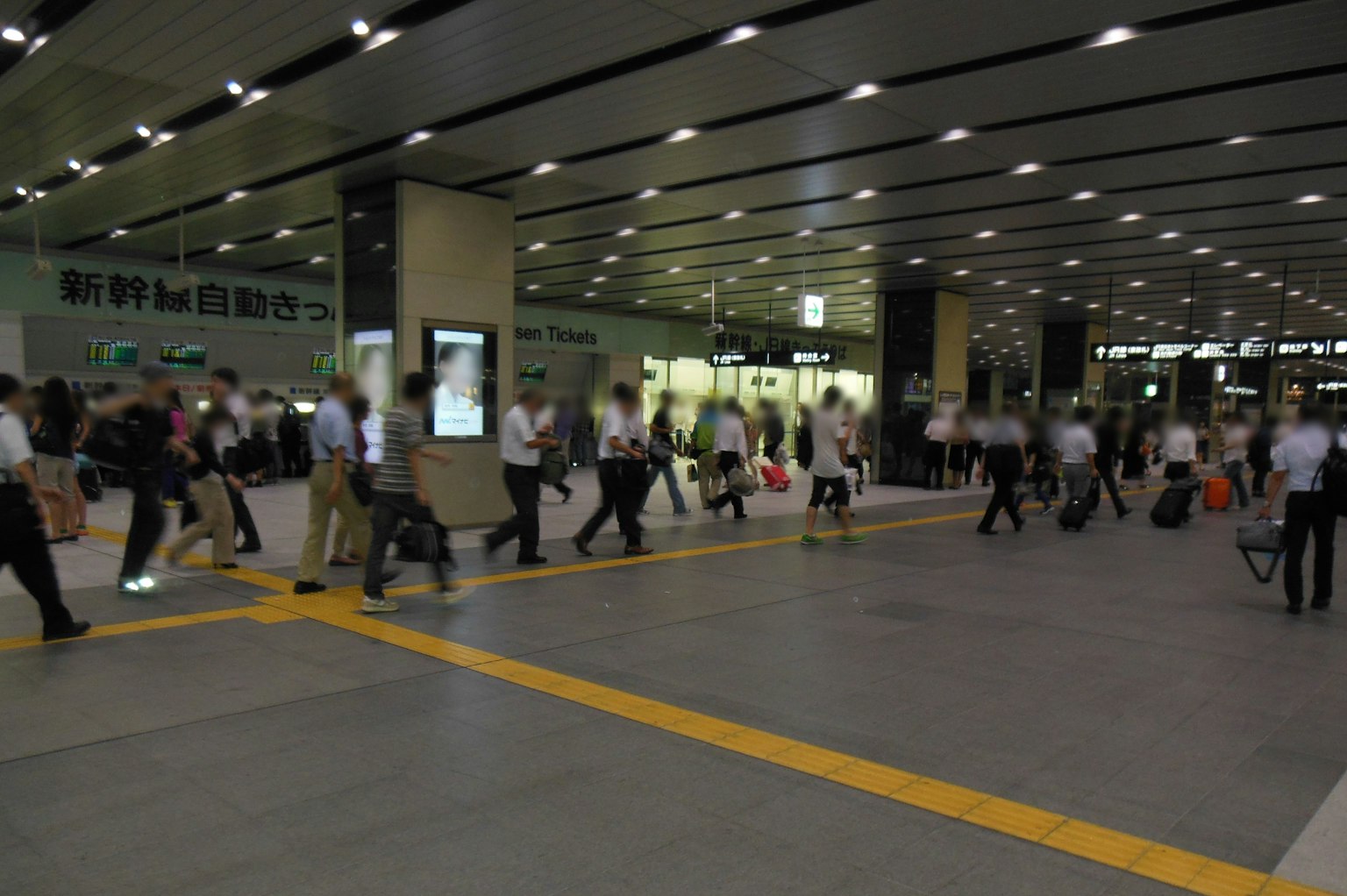 Corridoio affollato della stazione con persone che camminano e trasportano bagagli