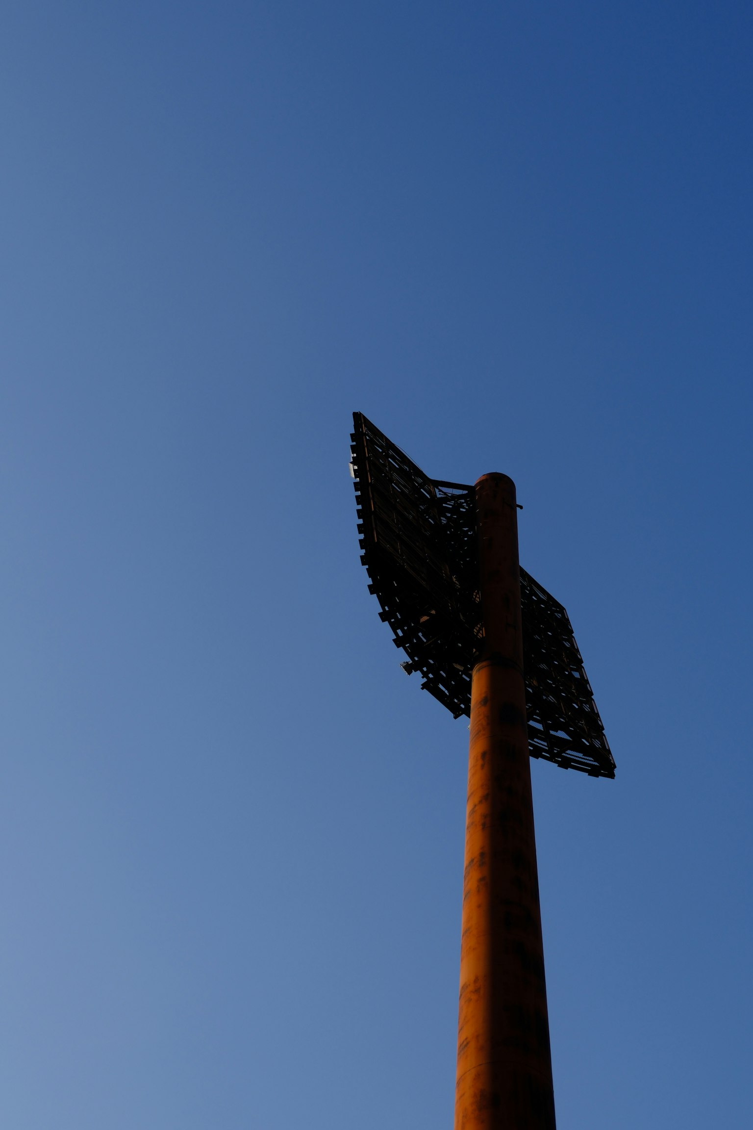 Alto poste de metal con una estructura única en la parte superior contra un cielo azul