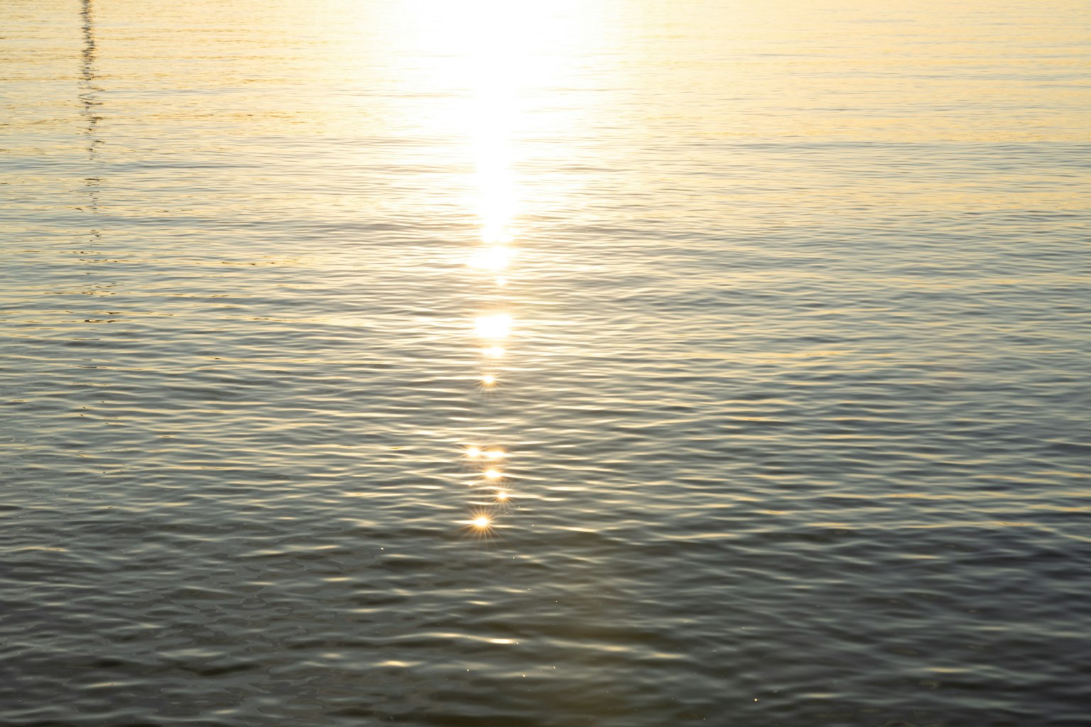 Superficie de agua tranquila reflejando la luz del atardecer