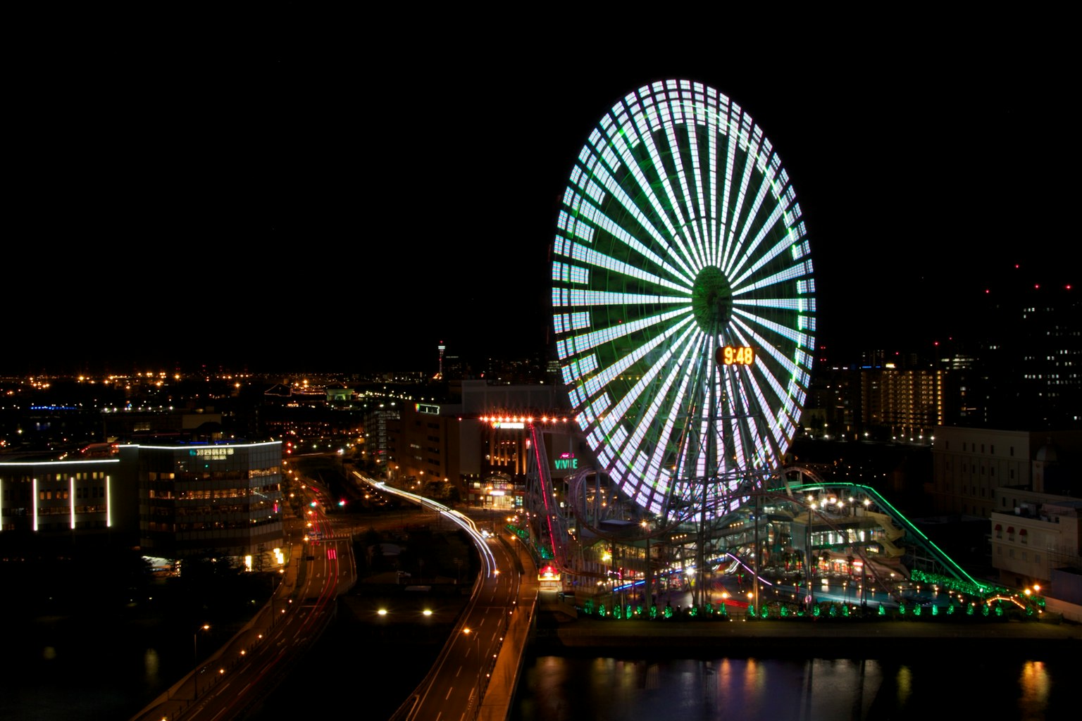 Vue nocturne d'une grande roue et de la ligne d'horizon de la ville