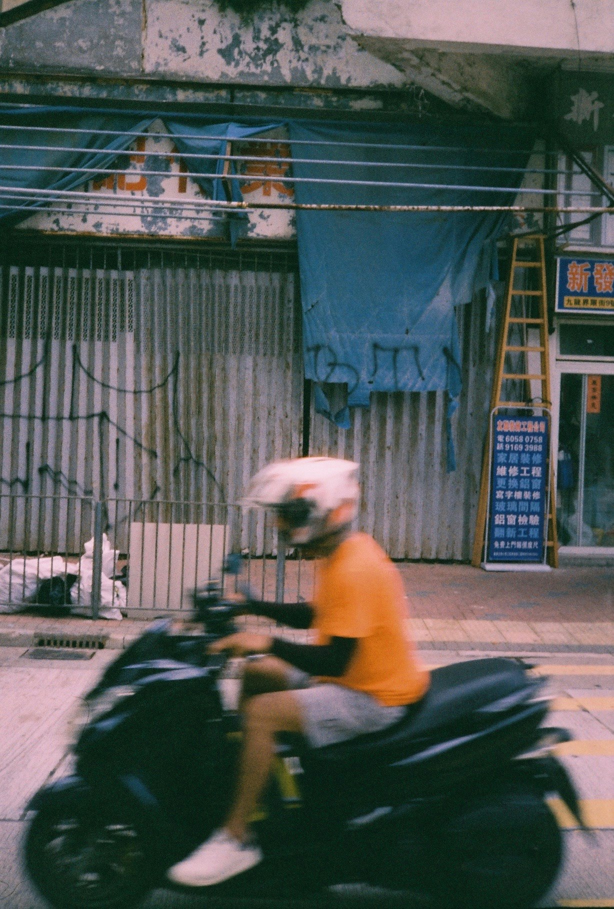 バイクが通り過ぎる路地の商店街の軒先