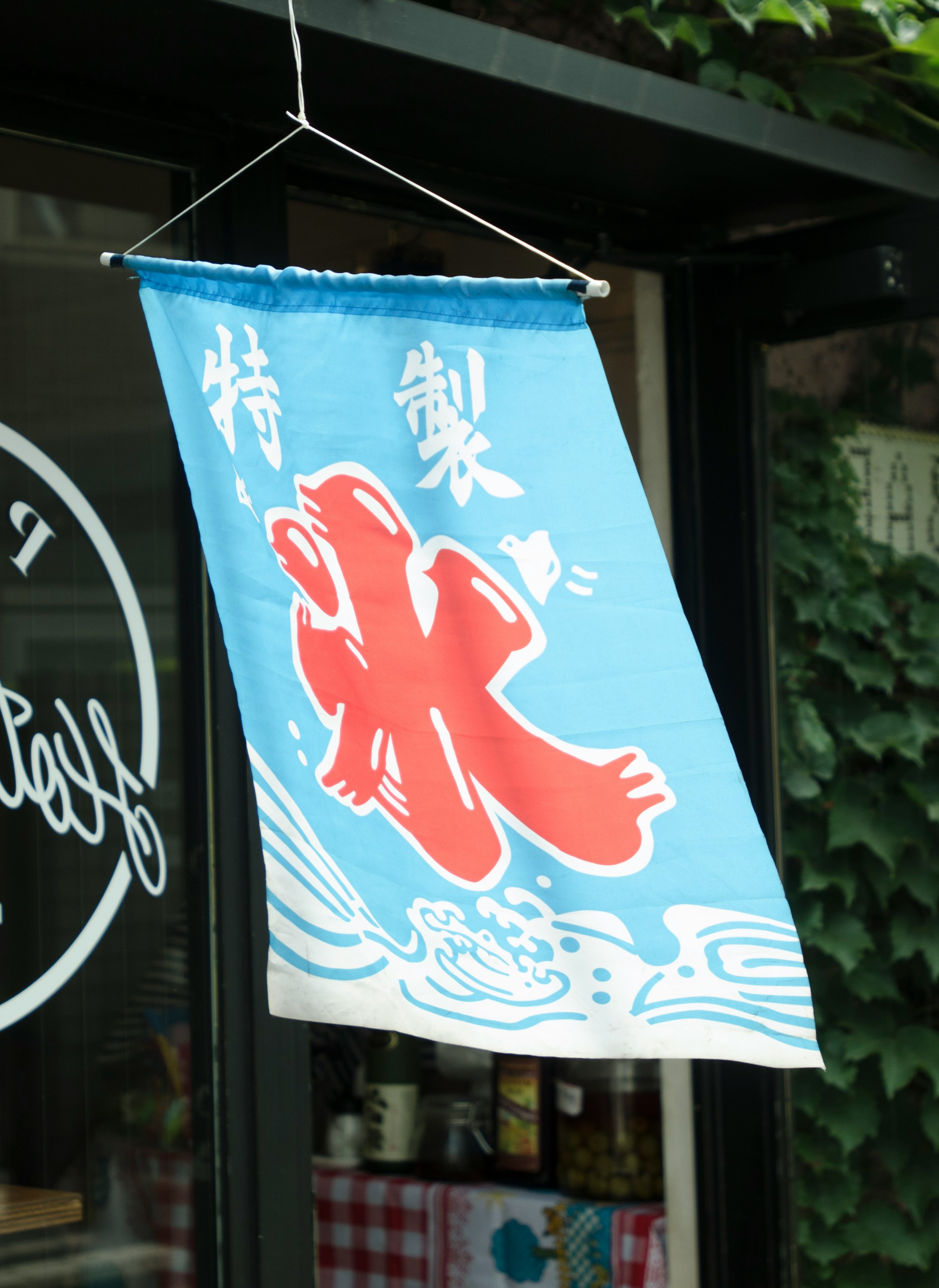 青い暖簾に赤い魚のイラストが描かれた店先
