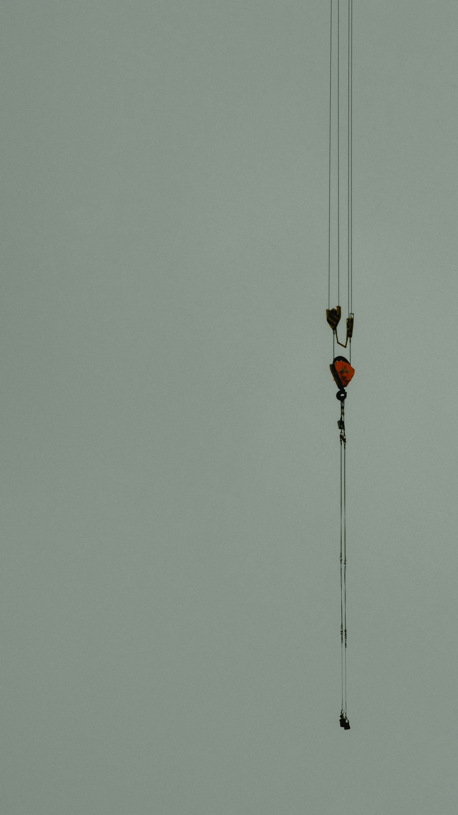 Une image simple avec un crochet de grue orange suspendu dans les airs