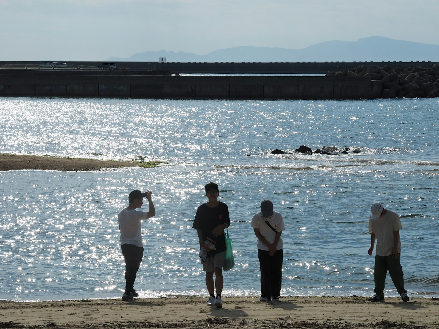 Silhouetten von Personen am Strand mit schimmerndem Wasser