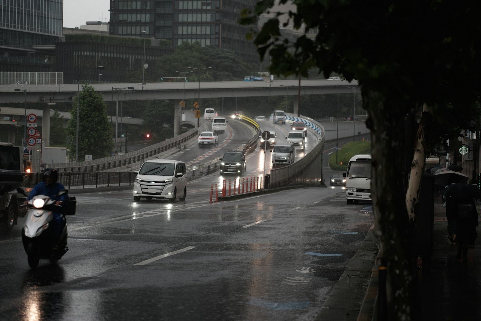 Strada urbana con auto e moto sotto la pioggia