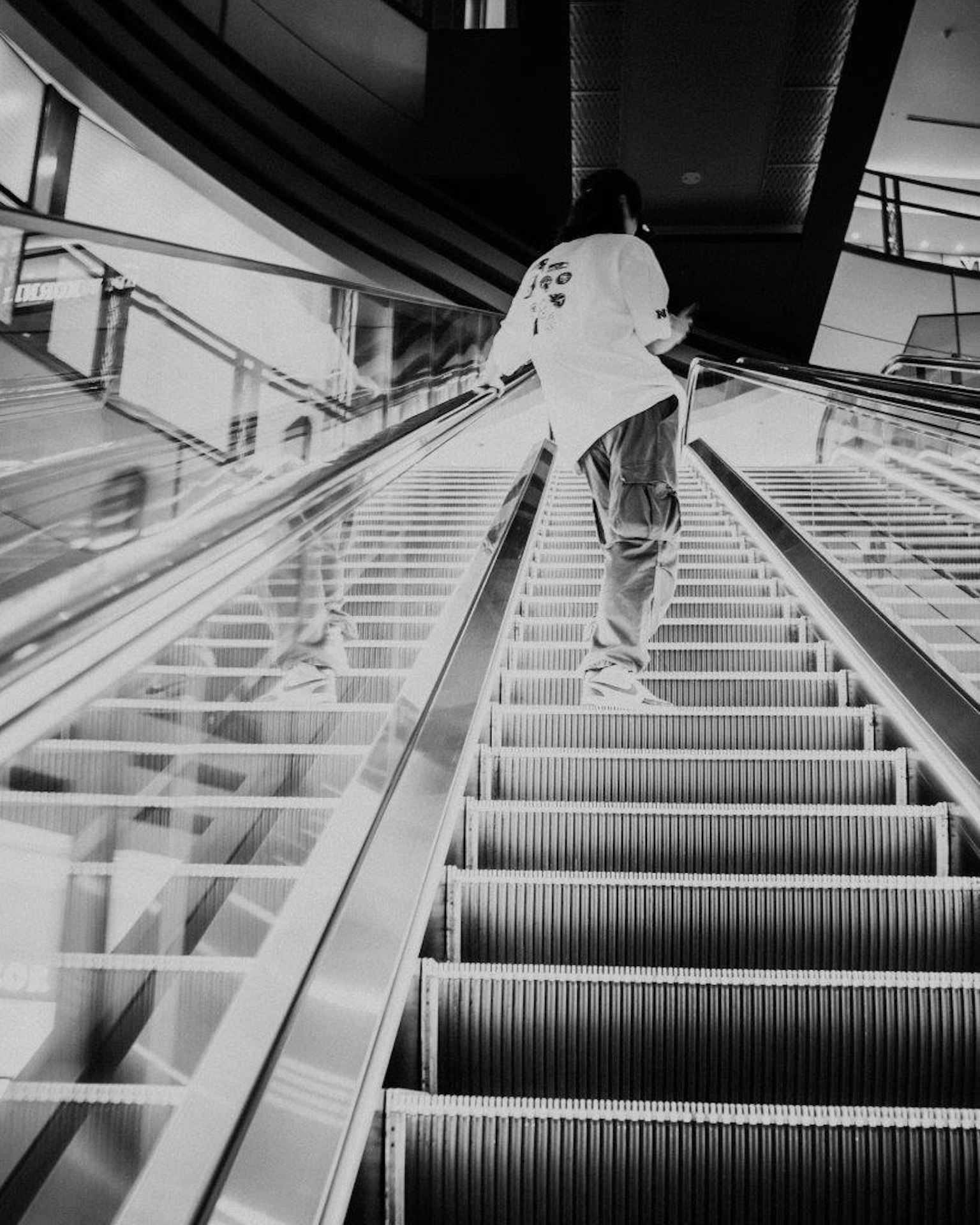 A person ascending a black and white escalator