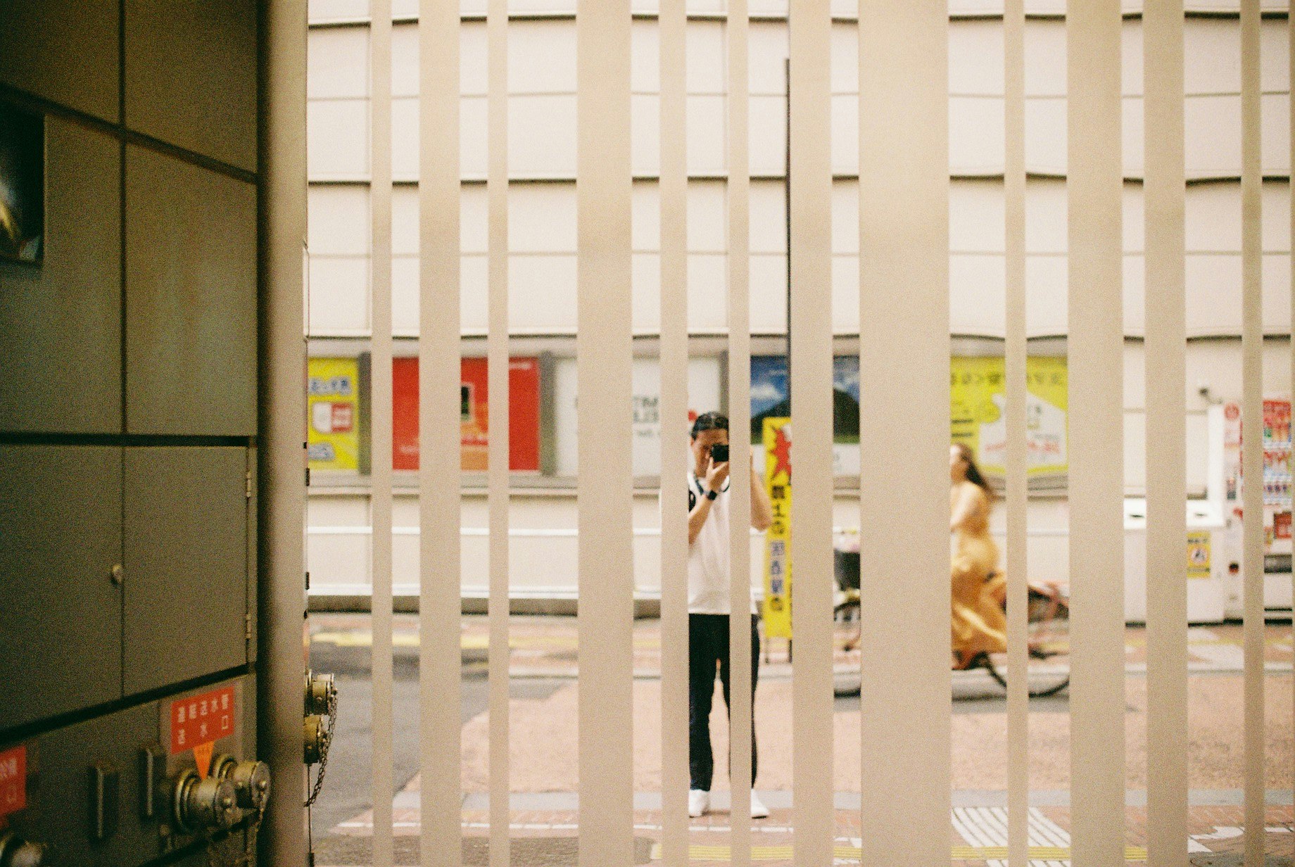 People standing in an indoor corridor behind a fence-like grid