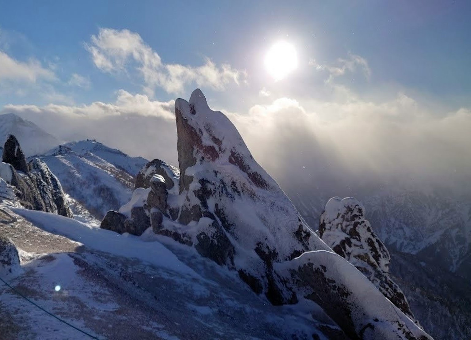 Snow-covered mountain peak with bright sun