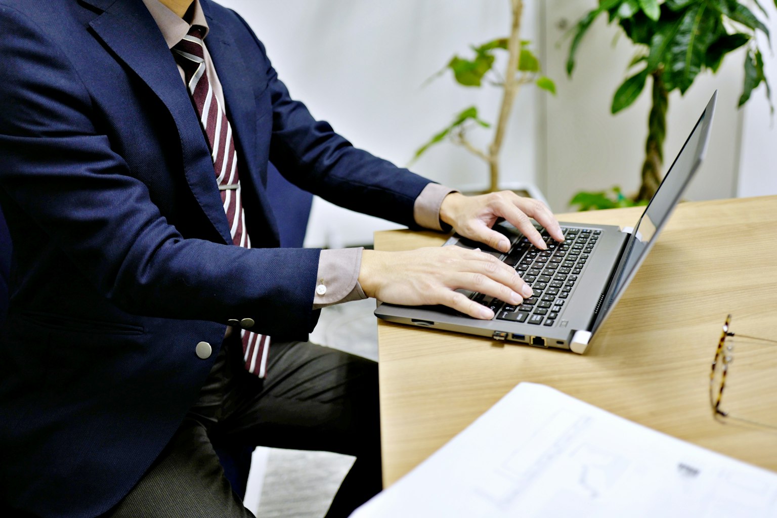 Geschäftsmann arbeitet an einem Laptop in einem Büro mit einer Pflanze im Hintergrund