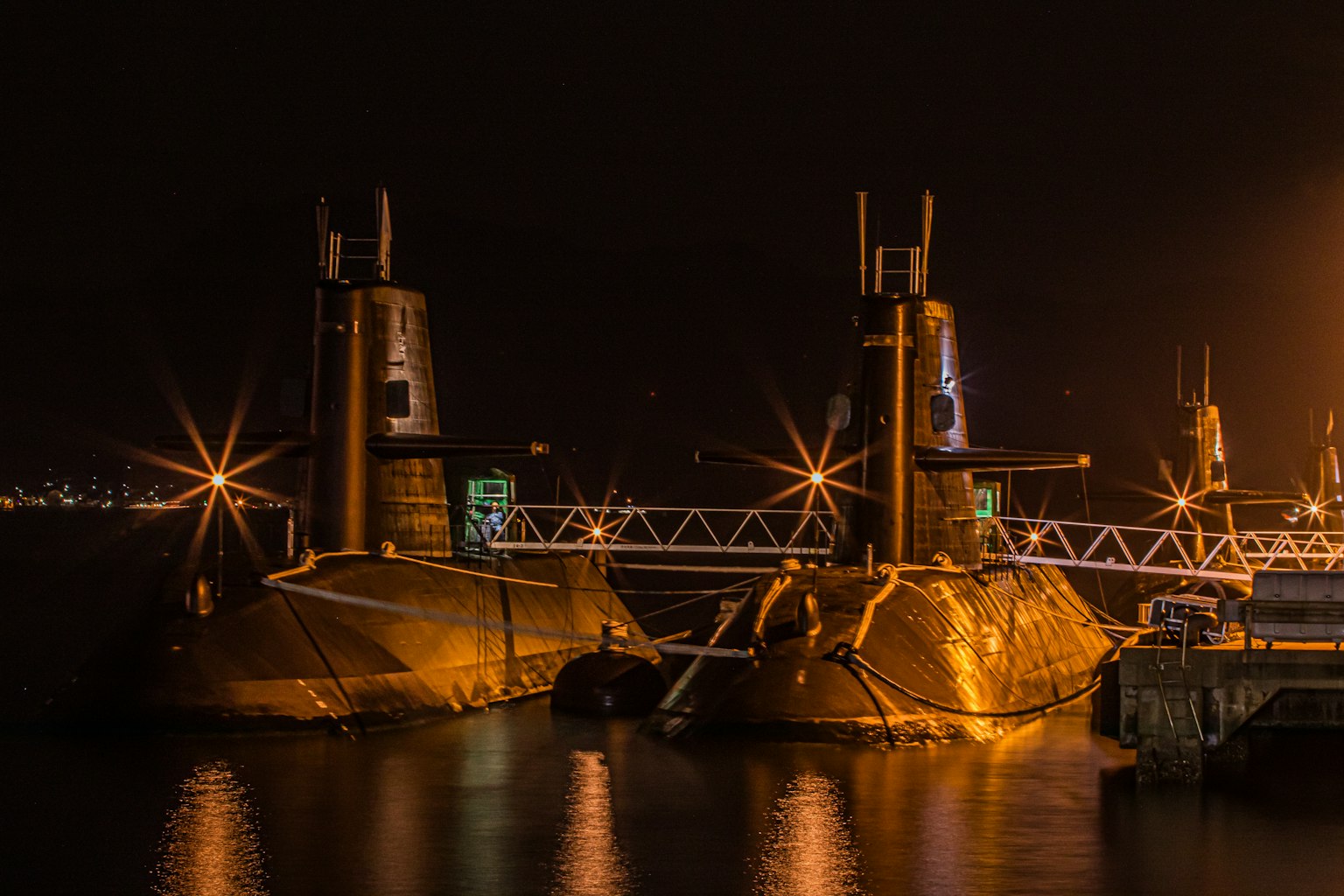 Deux sous-marins illuminés la nuit dans un port