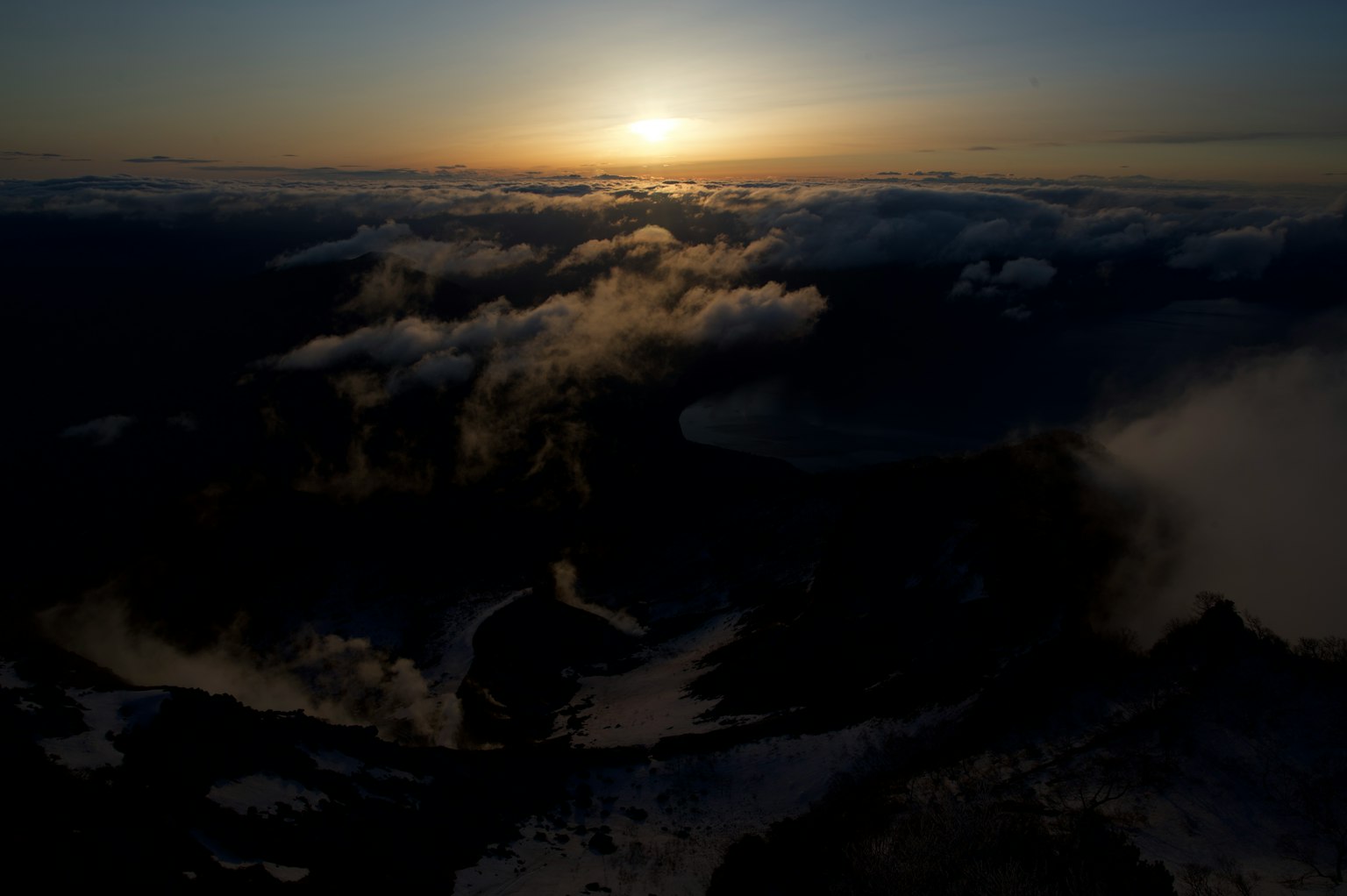 Aussicht von einem Berg mit Sonnenuntergangslicht, das durch Wolken bricht
