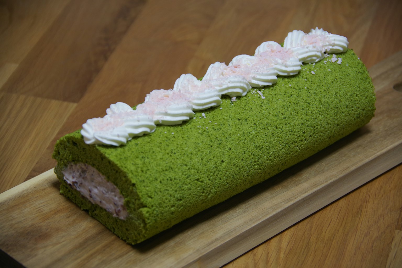 Matcha-Rollkuchen mit grünem Biskuit und rosa Topping