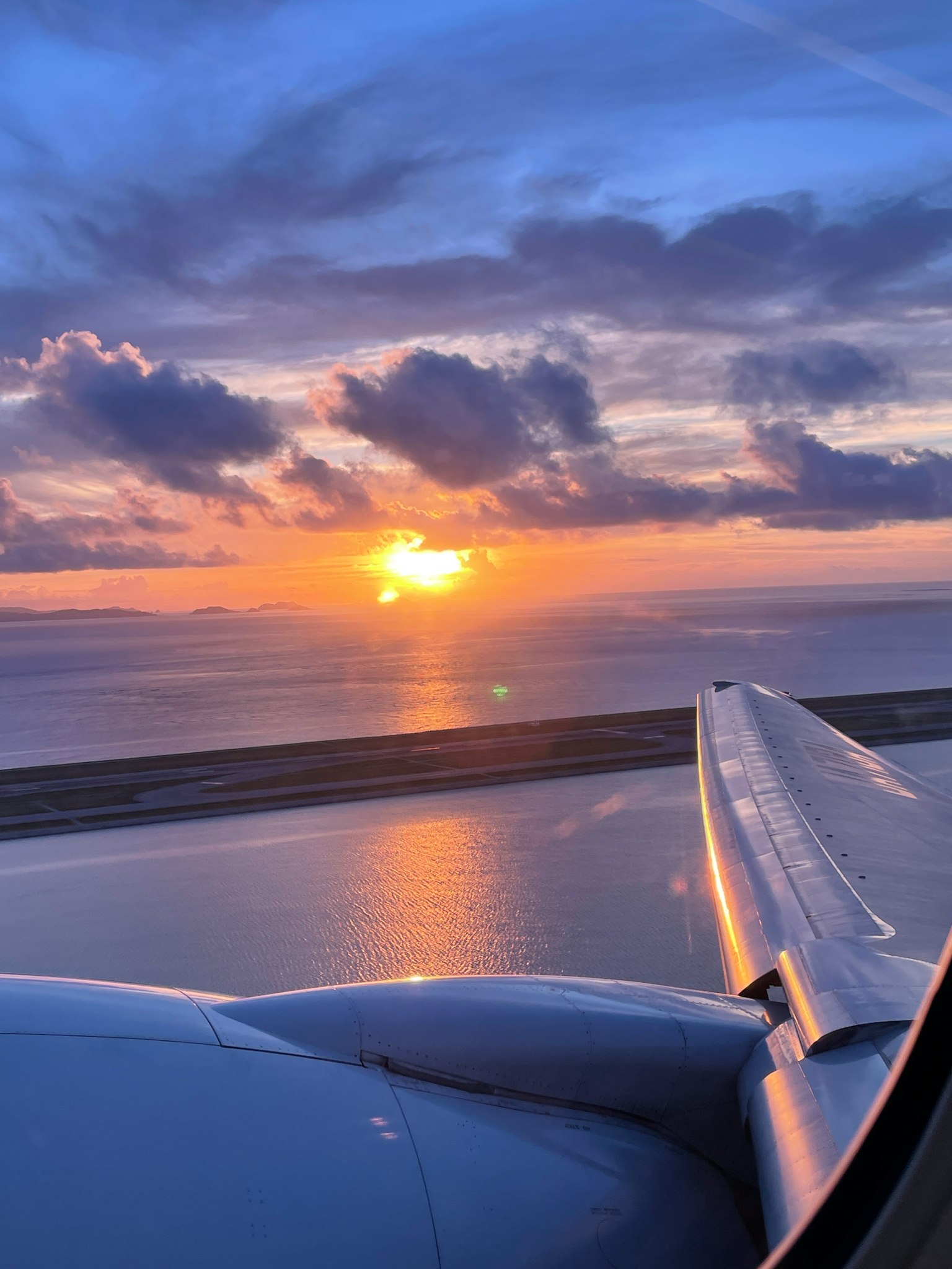 View of an airplane wing with a stunning sunset over the ocean