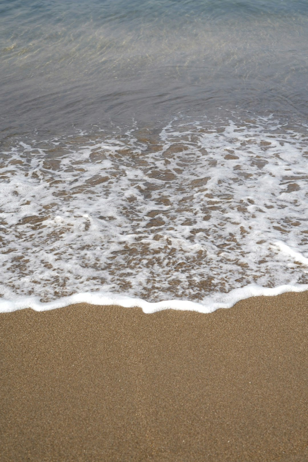波打ち際の砂と海面の泡立ち